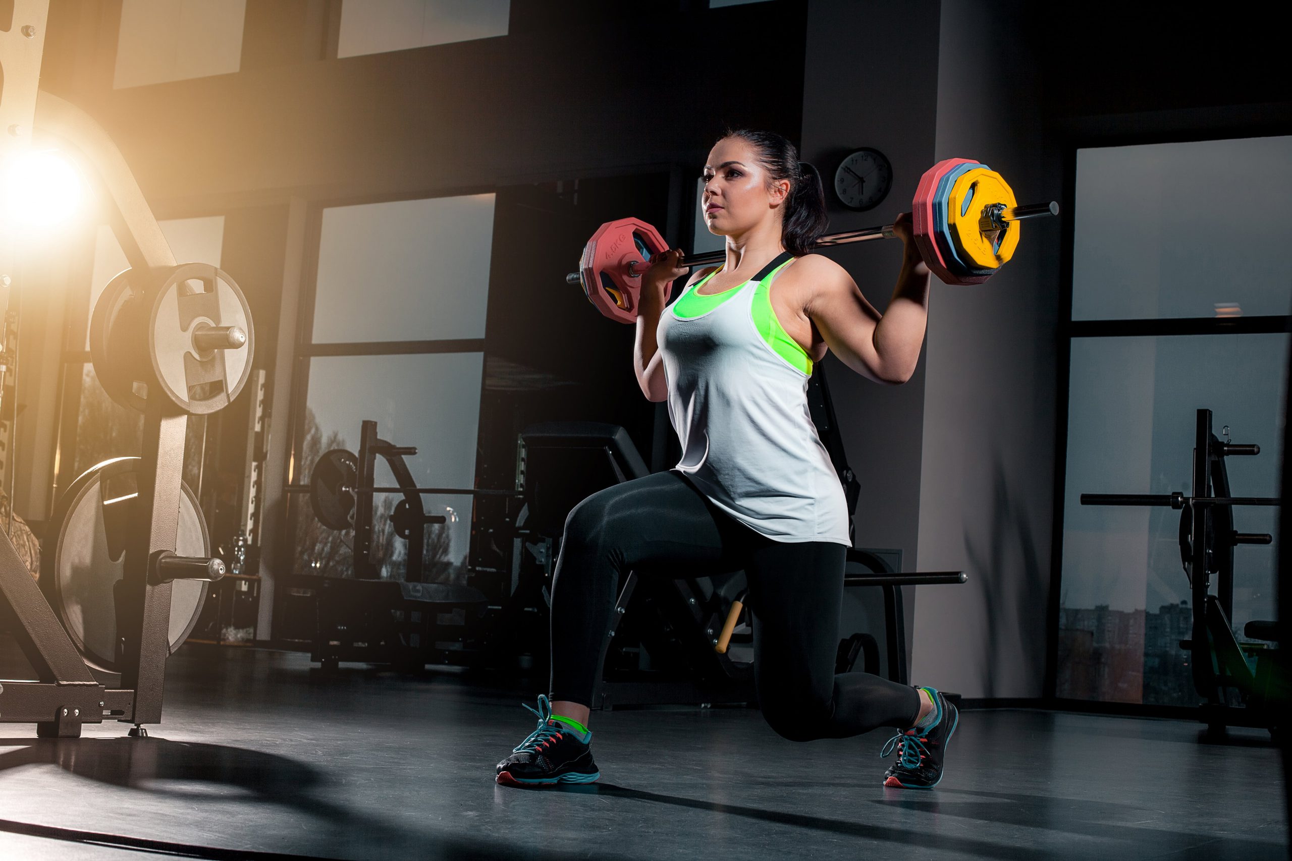 Frau macht Ausfallschritte mit Gewicht im Fitnessstudio